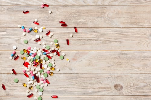 Preview: assorted pills and tablets top border over colored background. Many different pills and space text