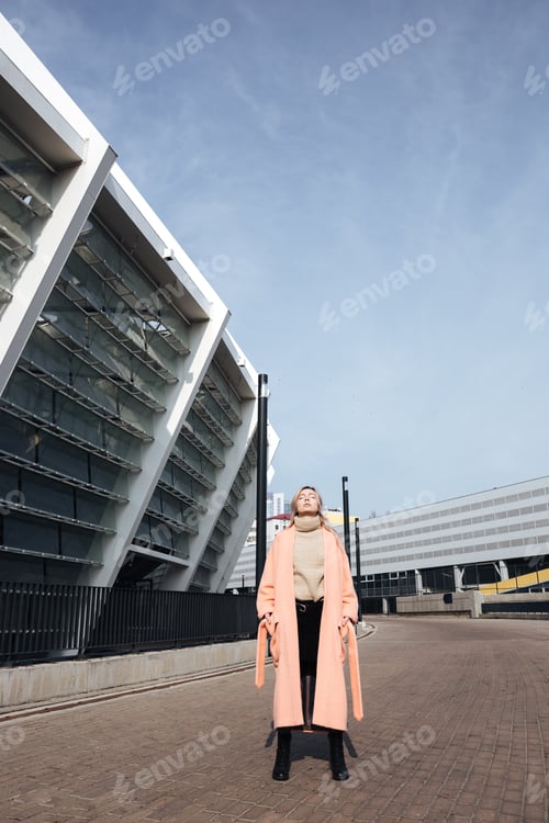 Preview: Serious young blonde lady walking outdoors.