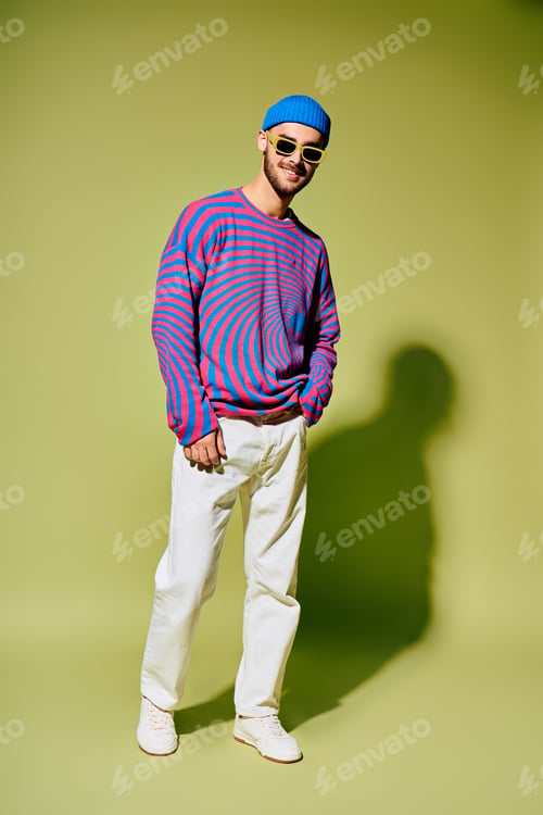 Preview: Handsome young man showcases stylish and vibrant fashion against a green studio backdrop