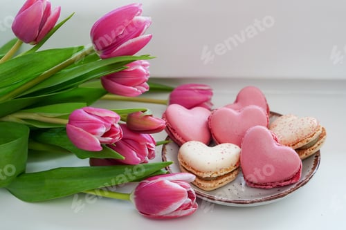 Preview: Sweet cookies macarons macaroons in heart shape and pink tulip flowers on windowsill at home