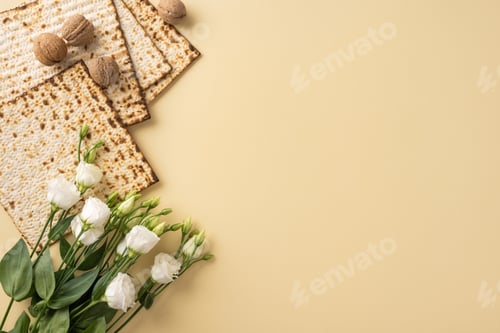 Preview: Top view of traditional Matzo bread, white flowers, and hazelnuts on a neutral beige background