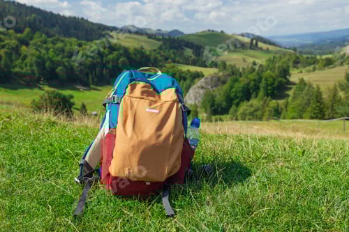 Preview: Backpack on Grassy Hill Overlooking Mountain Landscape