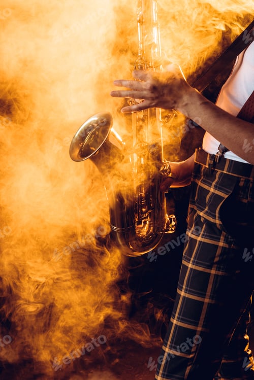 Preview: cropped shot of expressive young musician playing saxophone in smoke