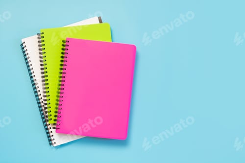 Preview: Colorful girlish school supplies, notebooks and pens on punchy blue. Top view, flat lay. Copy space.