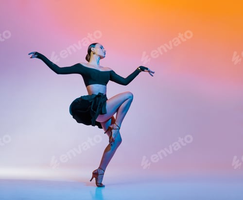 Preview: Stylish female dancer in black outfit posing in Latin dance move on vibrant gradient studio
