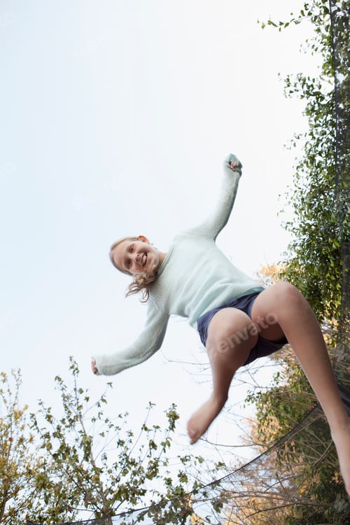 Preview: Girl jumping mid air on garden trampoline