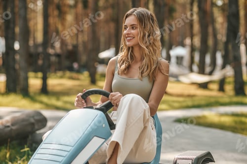 Preview: Smiling blonde woman sitting in a vehicle and looking enjoyed