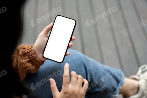 Preview: Close-up image of a woman using her smartphone while sitting outdoors street.
