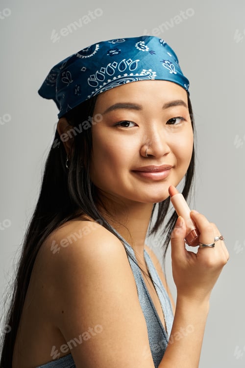 Preview: Captivating young woman with a blue bandana posing confidently in a soft studio setting