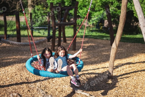 Preview: Two caucasian girls flying at speed with hair fluttering in the wind sitting on a round rope