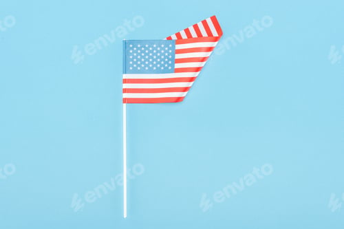 Preview: top view of american flag on stick on blue background