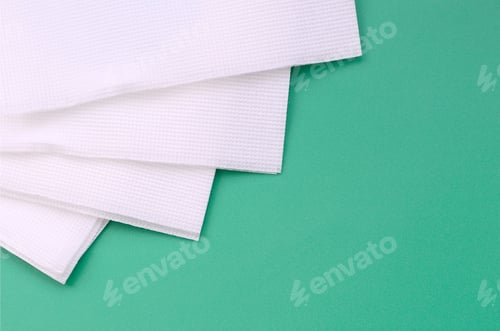 Preview: Several white paper napkins lie on a plastic green background