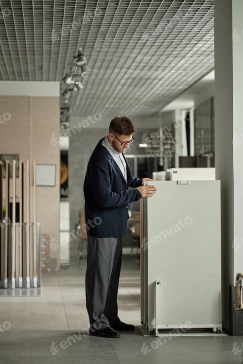 Preview: Caucasian Man Examining Display Stand in Modern Showroom