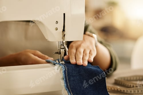 Preview: Closeup of the hand of a seamstress using a sewing machine. Fashion designer sewing denim fabric on