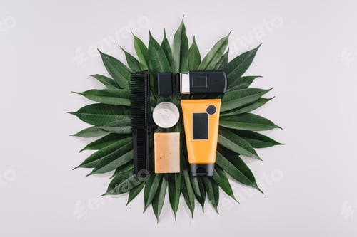 Preview: top view of arranged barber tools on green leaves isolated on grey