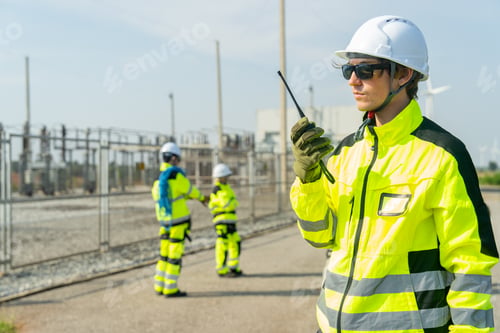 Preview: Wind turbine or windmill worker or technician man stand with hold walkie-talkie and stand near plant