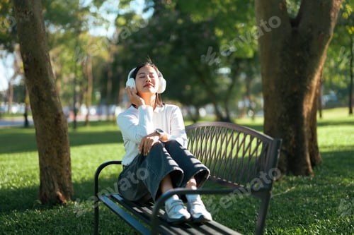Preview: Young woman enjoying music and relaxing in park