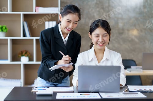 Preview: Two professional Asian business women discuss work using a laptop computer to work in the office.