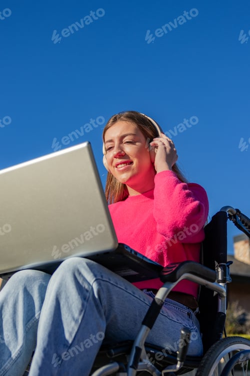 Preview: Woman with Laptop Using Headphones in Wheelchair
