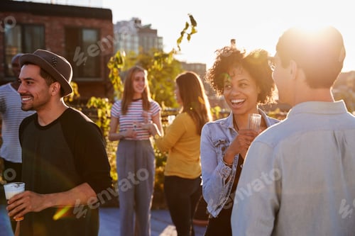 Preview: Happy friends at a rooftop party backlit by sunlight