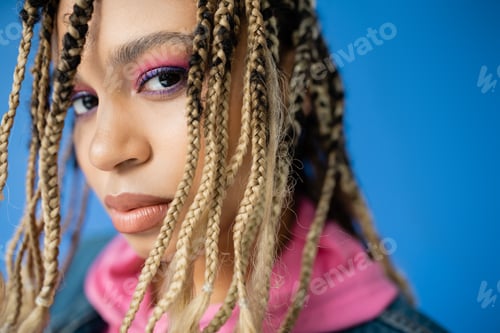 Preview: close up of dark skinned woman with dreadlocks on blue background, diversity, portrait, beautiful