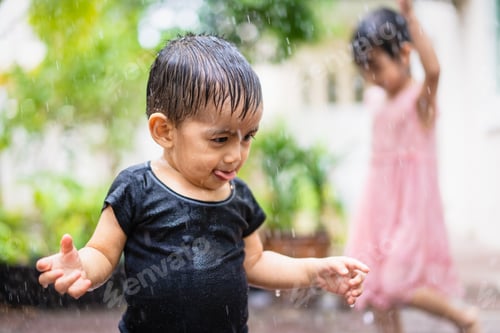 Preview: Happy asian toddler brother and sister are playing the rain outside the house together.