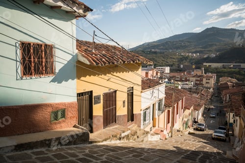 Preview: Sunny day view of a colorful hillside neighborhood with mountain backdrop.