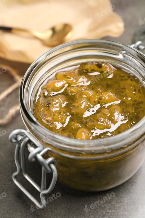 Preview: Jar of delicious gooseberry jam on grey table, closeup