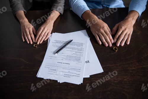 Preview: partial view of couple at table with divorce documents and rings