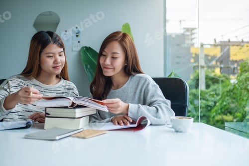 Preview: Two young female students tutoring and catching up workbook together