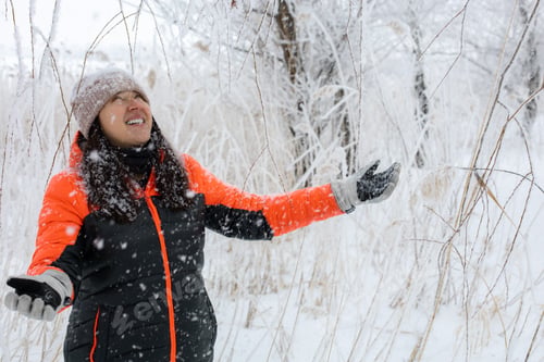 Preview: Blissful warmly dressed woman of middle age with face looking up smiling with teeth and arms