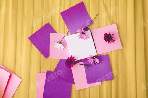 Preview: Mockup image with a white canvas surrounded by color papers and flowers