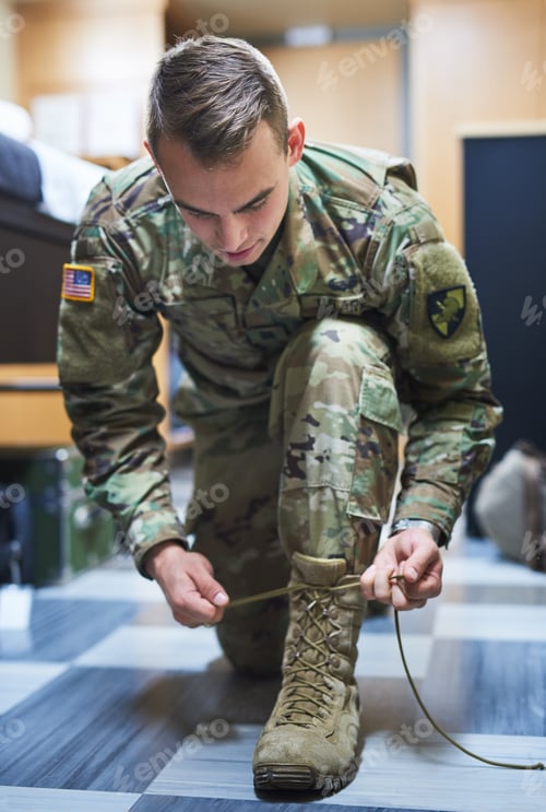 Preview: Shot of a young soldier tying his boot shoelaces in the dorms of a military academy
