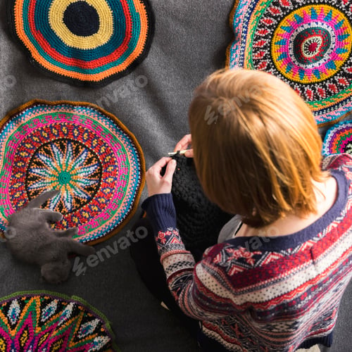 Preview: Overhead view of woman sitting on floor crocheting, surrounded by crochet circles