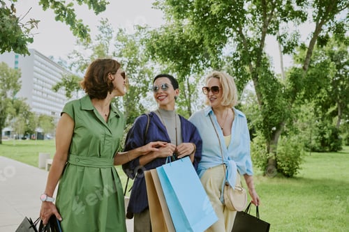 Preview: Three Middle Aged Women Chatting While Walking Outdoors with Bags