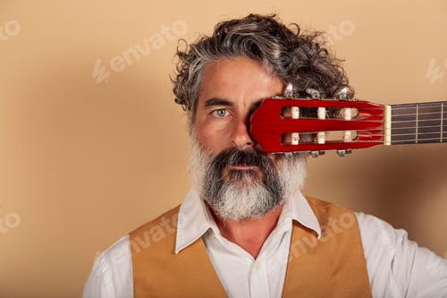 Preview: closeup portrait of a bearded man with spanish guitar on a yellow background