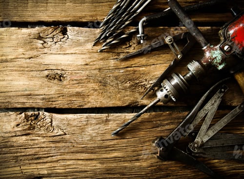 Preview: Old drill, compasses, pliers and drills on a wooden background.