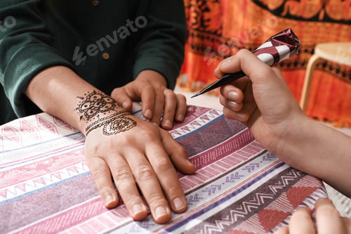 Preview: Master making henna tattoo on hand, closeup. Traditional mehndi