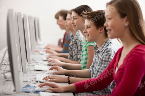 Preview: A group of young people, boys and girls, working at computer screens in class.