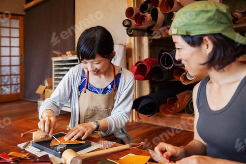 Preview: Two Japanese women sitting at a table, working in a leather shop.