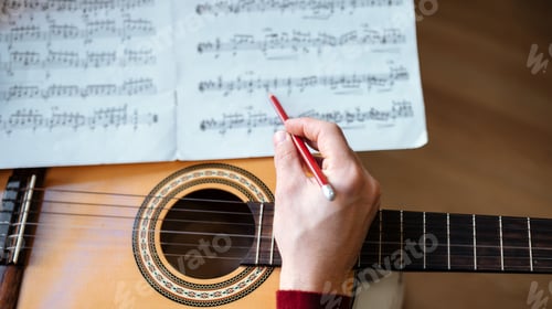 Preview: Man hands with sheet music playing guitar