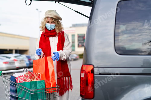 Preview: Woman putting shopping bags in the car during pandemic
