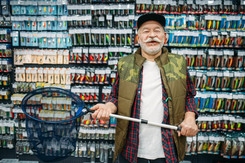 Preview: Happy angler holds net in fishing shop