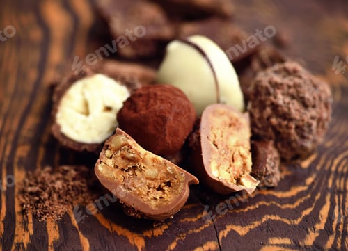 Preview: Handmade chocolate candies and pieces of chocolate on wooden bac