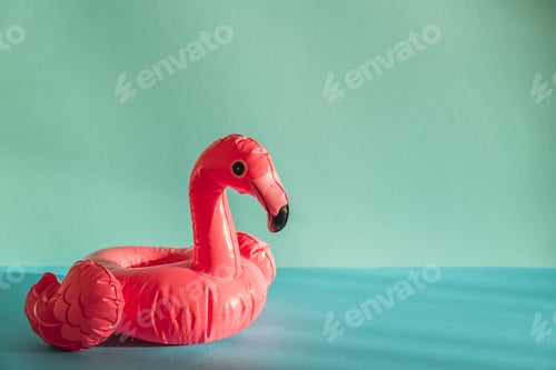 Preview: Pink Flamingo Shaped Pool Float on Turquoise Water under Sunlight. Front view