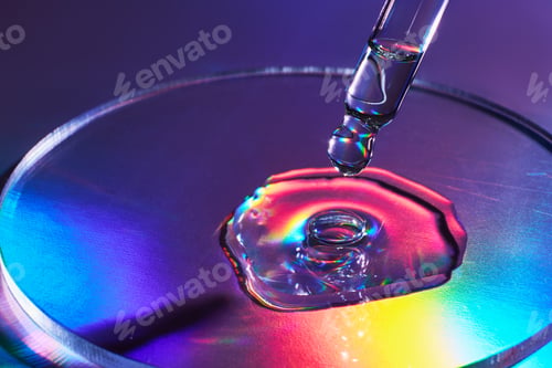 Preview: Pipette with sample of cosmetic product in petri dish on iridescent holographic background