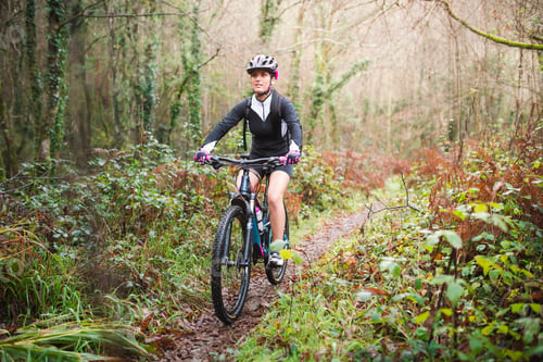Preview: Female mountain biker riding her bike on a trail in forest