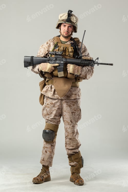 Preview: Soldier stands with rifle in uniform in studio setting during daylight hours