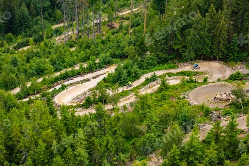 Preview: Bicyclists ride on hill slope trail park surrounded by forest