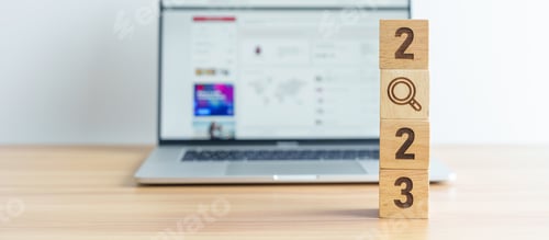 Preview: 2023 block with magnifying glass icon against laptop background.